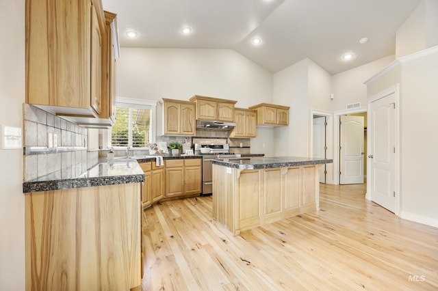 kitchen featuring visible vents, high vaulted ceiling, a kitchen bar, stainless steel range with gas cooktop, and under cabinet range hood