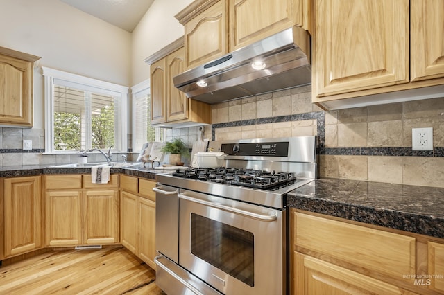 kitchen featuring stainless steel range with gas stovetop, under cabinet range hood, tile counters, and light brown cabinetry