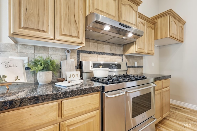 kitchen featuring light brown cabinetry, under cabinet range hood, double oven range, and tile countertops
