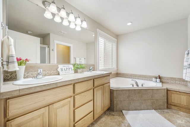 full bath featuring a sink, a garden tub, double vanity, and visible vents