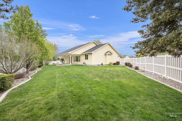 rear view of house featuring a yard, a fenced backyard, and a patio area