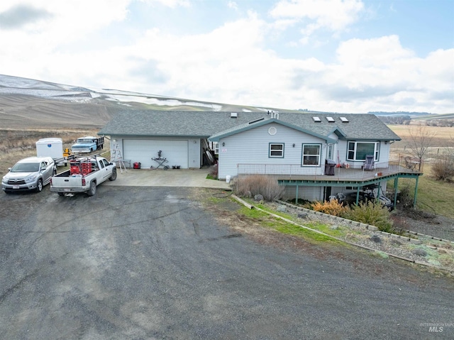 ranch-style home with a garage and a deck with mountain view