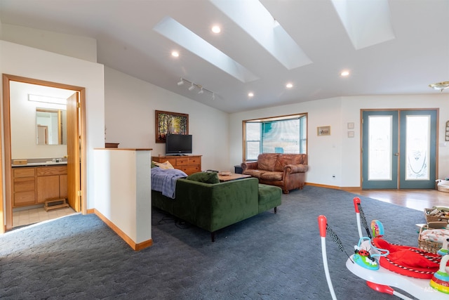 carpeted living room with french doors, track lighting, and lofted ceiling with skylight