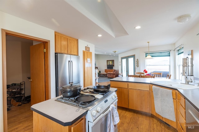 kitchen with appliances with stainless steel finishes, sink, a center island, a healthy amount of sunlight, and light hardwood / wood-style flooring