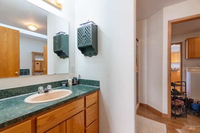 bathroom with vanity, washer / clothes dryer, a shower with shower door, and hardwood / wood-style floors