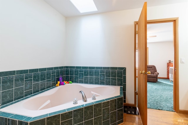 bathroom with a skylight and tiled tub