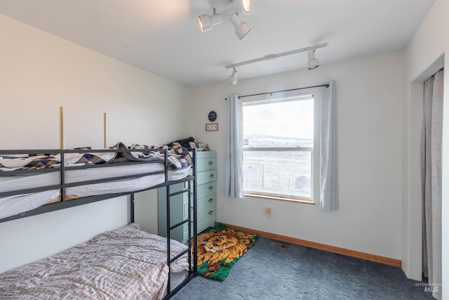 carpeted bedroom featuring track lighting