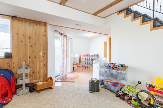 game room featuring a healthy amount of sunlight, carpet flooring, and wood walls