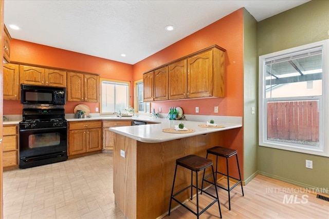 kitchen with a breakfast bar, sink, kitchen peninsula, and black appliances