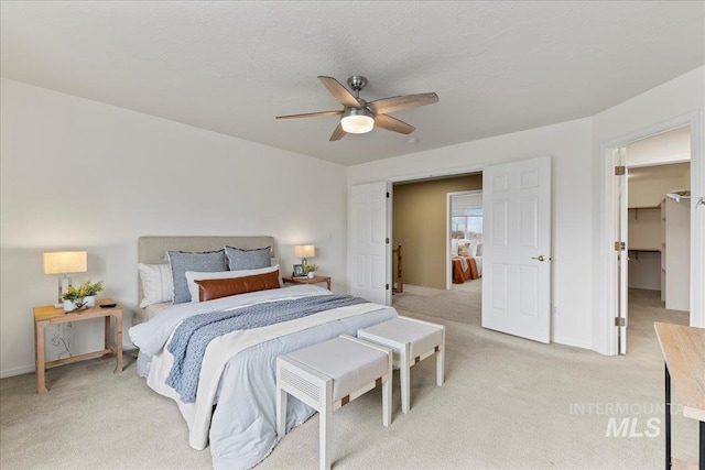 carpeted bedroom featuring ceiling fan, a spacious closet, and a textured ceiling