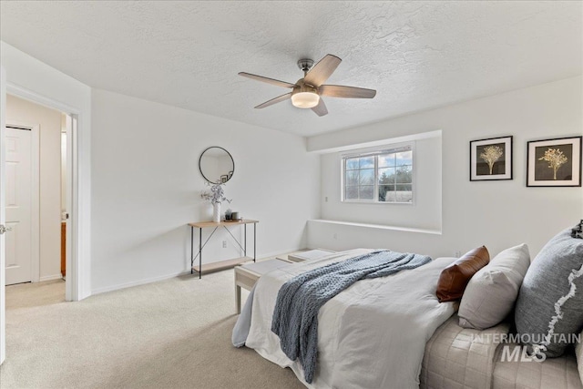 bedroom featuring ceiling fan, light colored carpet, and a textured ceiling