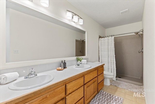 bathroom featuring backsplash, vanity, walk in shower, toilet, and a textured ceiling