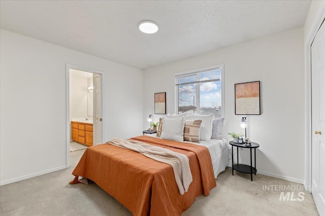 carpeted bedroom featuring ensuite bathroom and a textured ceiling