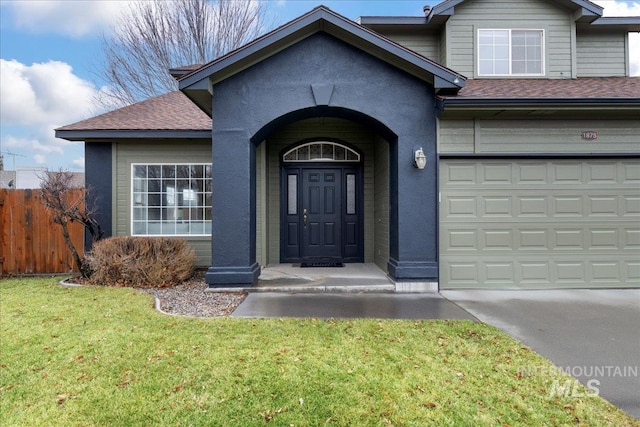 property entrance featuring a garage and a lawn