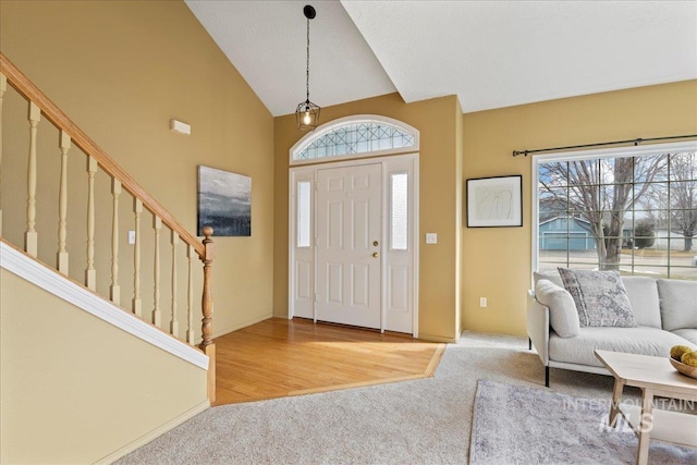 entryway with light colored carpet and high vaulted ceiling