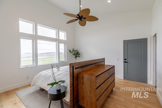 bedroom featuring light wood-style floors, ceiling fan, high vaulted ceiling, and baseboards