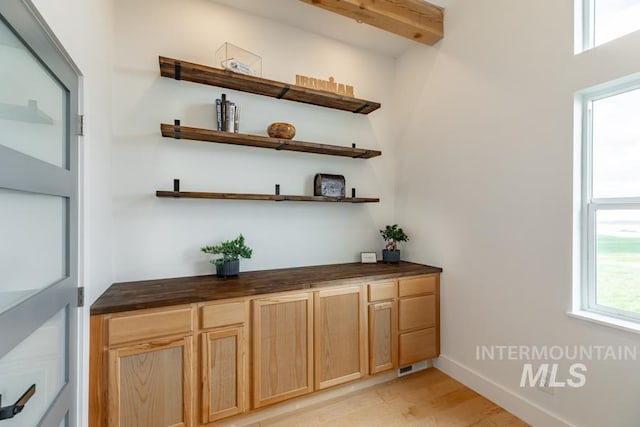 bar with visible vents, light wood-type flooring, and baseboards