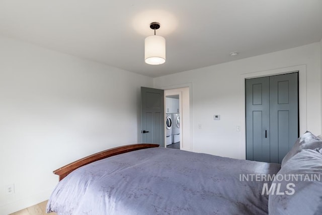 bedroom with baseboards, wood finished floors, and washer and clothes dryer