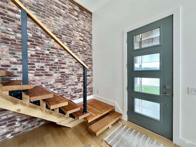 entrance foyer with a high ceiling, wood finished floors, and brick wall