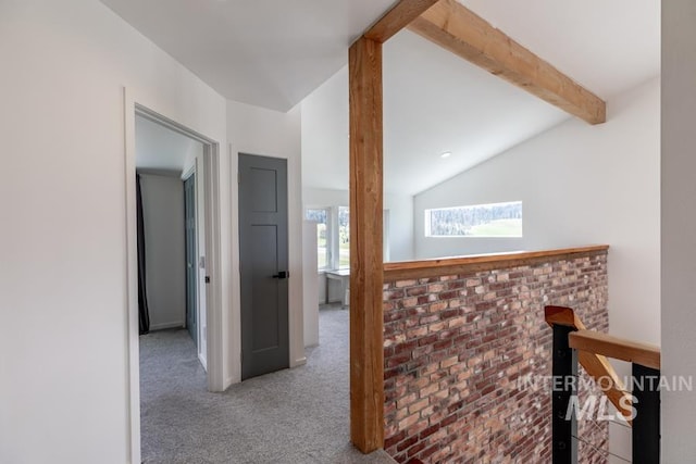 corridor featuring brick wall, lofted ceiling with beams, and carpet flooring