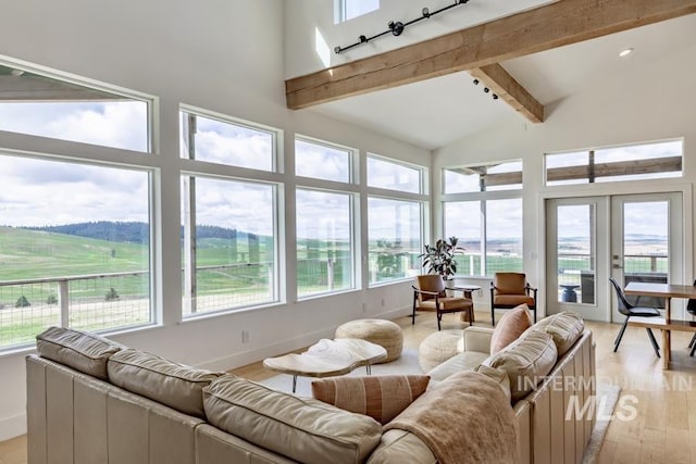 living room featuring baseboards, light wood finished floors, beam ceiling, high vaulted ceiling, and french doors