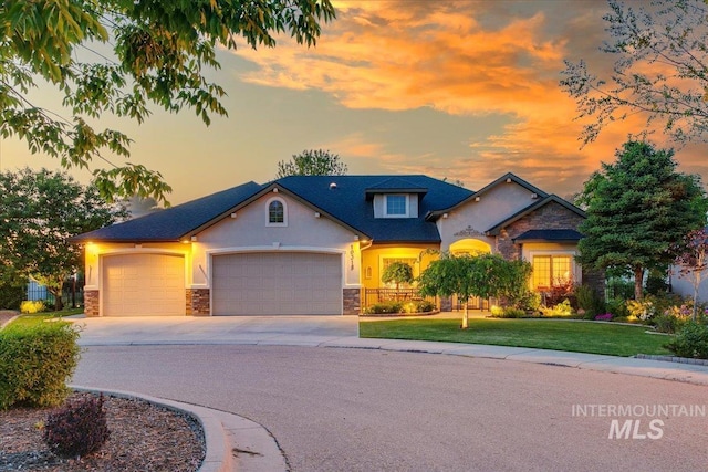 10318 W Adirondack Ct, Star, ID 83669 - view of front of home with stone siding, an attached garage, concrete driveway, a lawn, and stucco siding