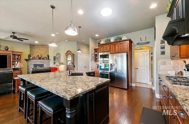 10318 W Adirondack Ct, Star, ID 83669 - kitchen with stainless steel appliances, a sink, ceiling fan, dark wood-style flooring, and brown cabinetry