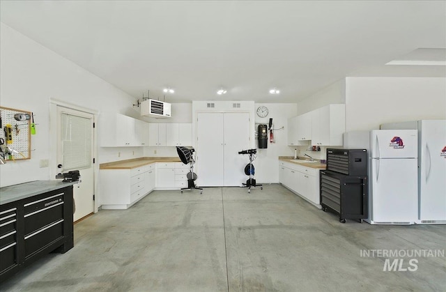 10318 W Adirondack Ct, Star, ID 83669 - kitchen featuring concrete flooring, a sink, freestanding refrigerator, light countertops, and white cabinets