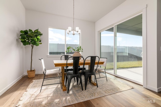 dining room featuring an inviting chandelier, wood finished floors, and a healthy amount of sunlight