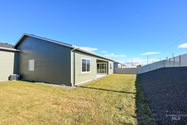 rear view of house featuring a yard, central AC, and a fenced backyard