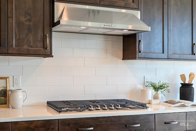 kitchen with under cabinet range hood, stainless steel gas cooktop, light countertops, and dark brown cabinets