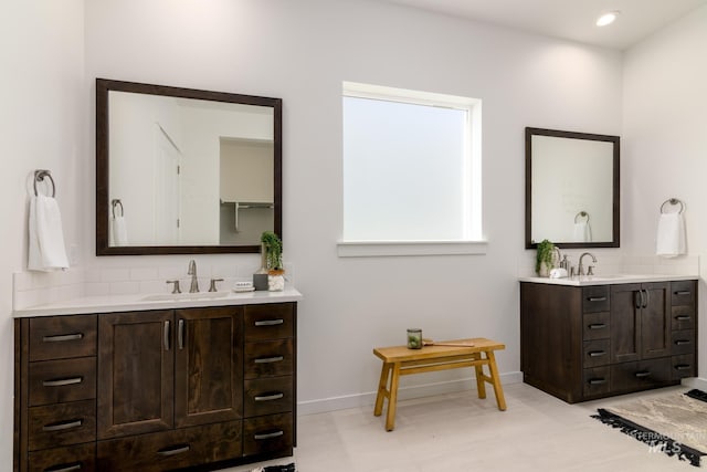 bathroom with tasteful backsplash, two vanities, a sink, and baseboards