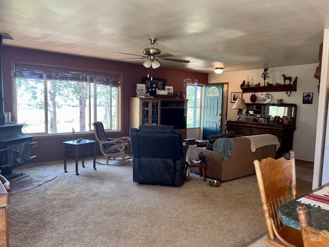 carpeted living room featuring ceiling fan and a wood stove