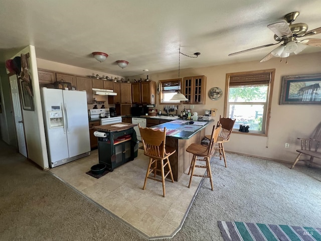 kitchen with white appliances, decorative light fixtures, light carpet, a kitchen breakfast bar, and sink