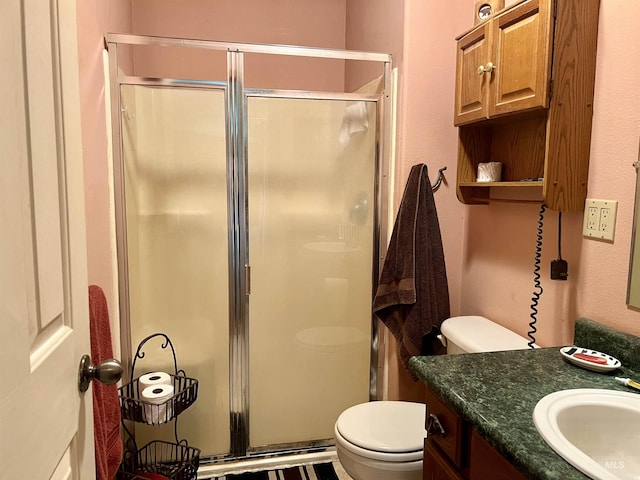 bathroom with toilet, a shower with door, and vanity