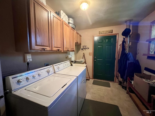 clothes washing area with light tile patterned flooring, cabinets, and washing machine and clothes dryer