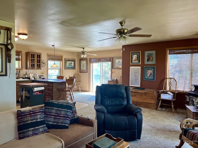 living room featuring ceiling fan, light colored carpet, and a textured ceiling