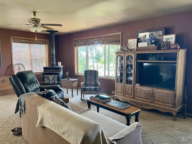 carpeted living room featuring a wood stove and ceiling fan