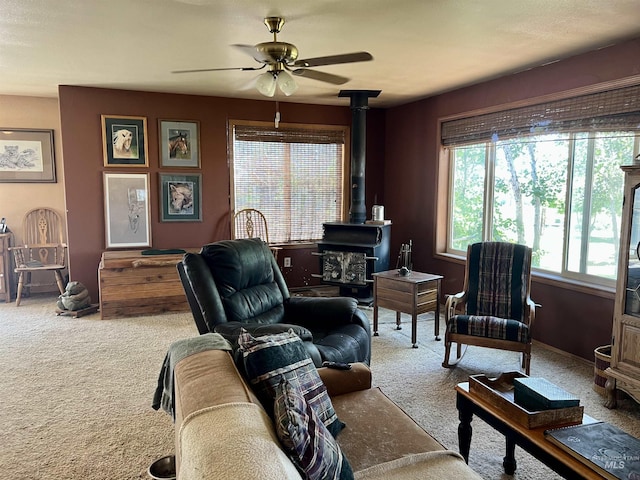 carpeted living room with ceiling fan and a wood stove