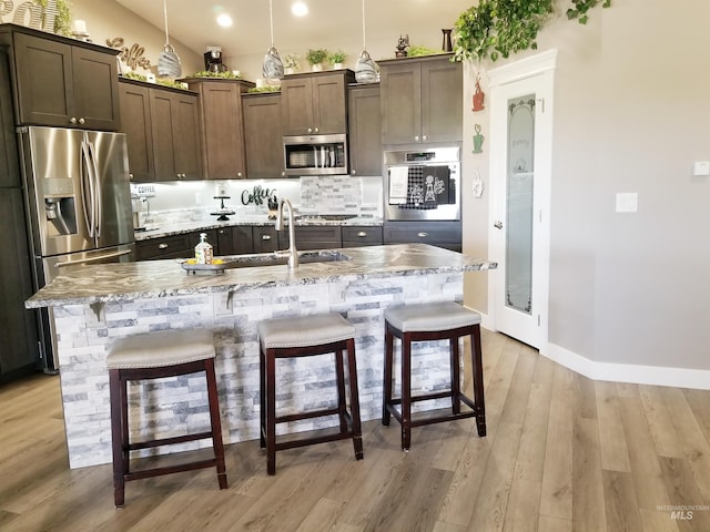 3847 N 2456 E, Filer, ID 83328 - kitchen featuring a kitchen breakfast bar, light wood finished floors, stainless steel appliances, a sink, and backsplash