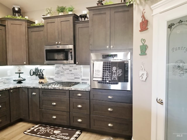 3847 N 2456 E, Filer, ID 83328 - kitchen with backsplash, light stone counters, light wood-style floors, and appliances with stainless steel finishes