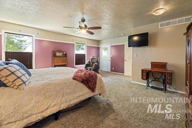 carpeted bedroom with a textured ceiling, multiple windows, and visible vents