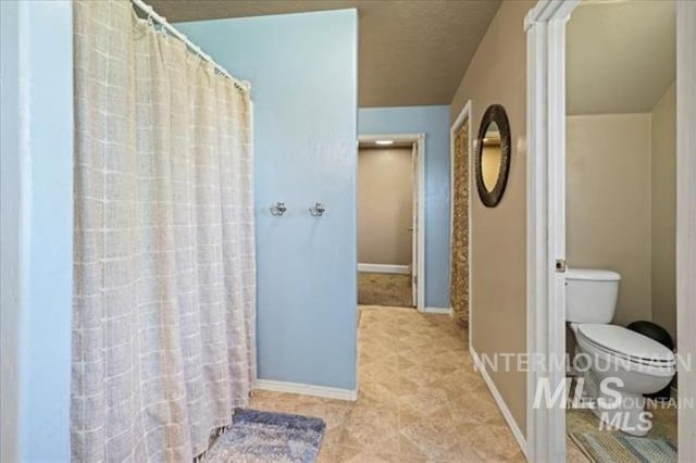 full bath with toilet, baseboards, and a shower with shower curtain