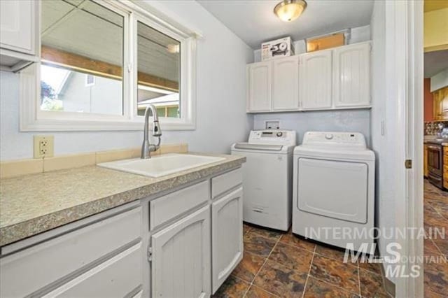 laundry room with a sink, stone finish floor, washing machine and clothes dryer, and cabinet space