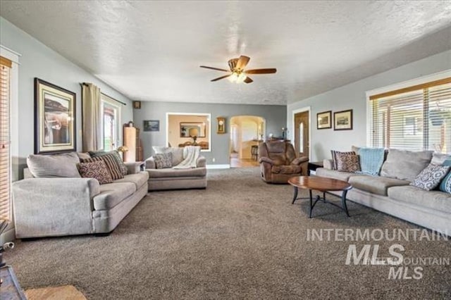 living area featuring arched walkways, carpet floors, a wealth of natural light, and a ceiling fan