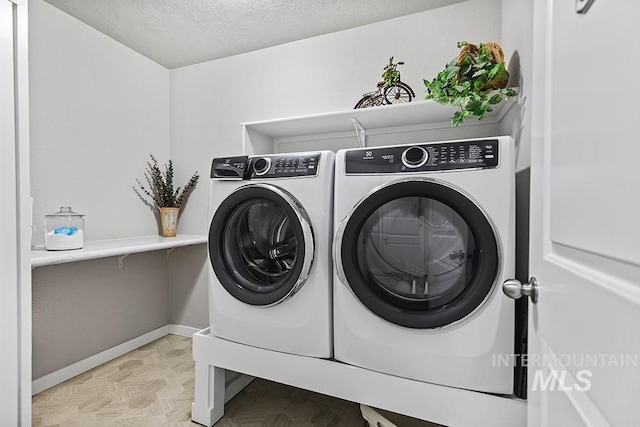 laundry area featuring a textured ceiling and washing machine and clothes dryer