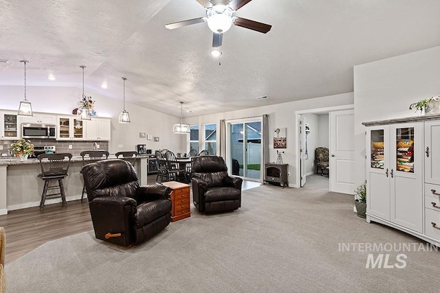 living room with lofted ceiling, ceiling fan, and a textured ceiling