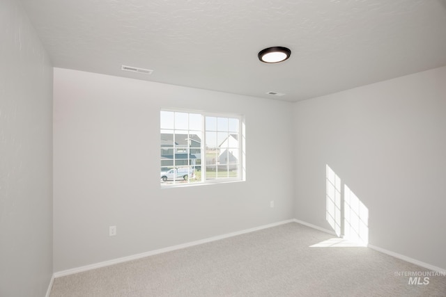 carpeted empty room with a textured ceiling