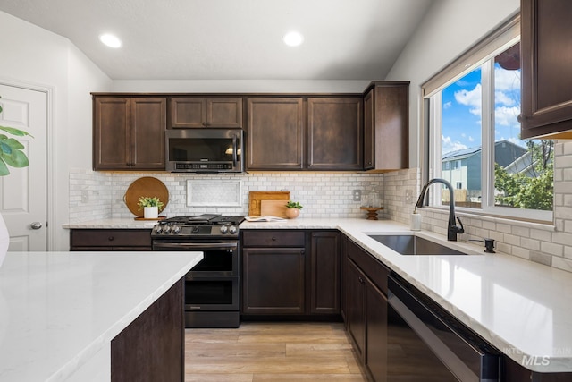 12850 Conner St, Caldwell, ID 83607 - kitchen featuring stainless steel appliances, a sink, dark brown cabinetry, light wood finished floors, and plenty of natural light