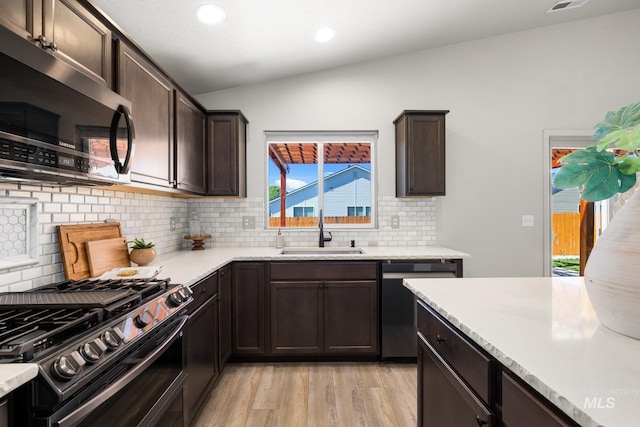 12850 Conner St, Caldwell, ID 83607 - kitchen with a sink, appliances with stainless steel finishes, vaulted ceiling, dark brown cabinets, and light wood-style flooring